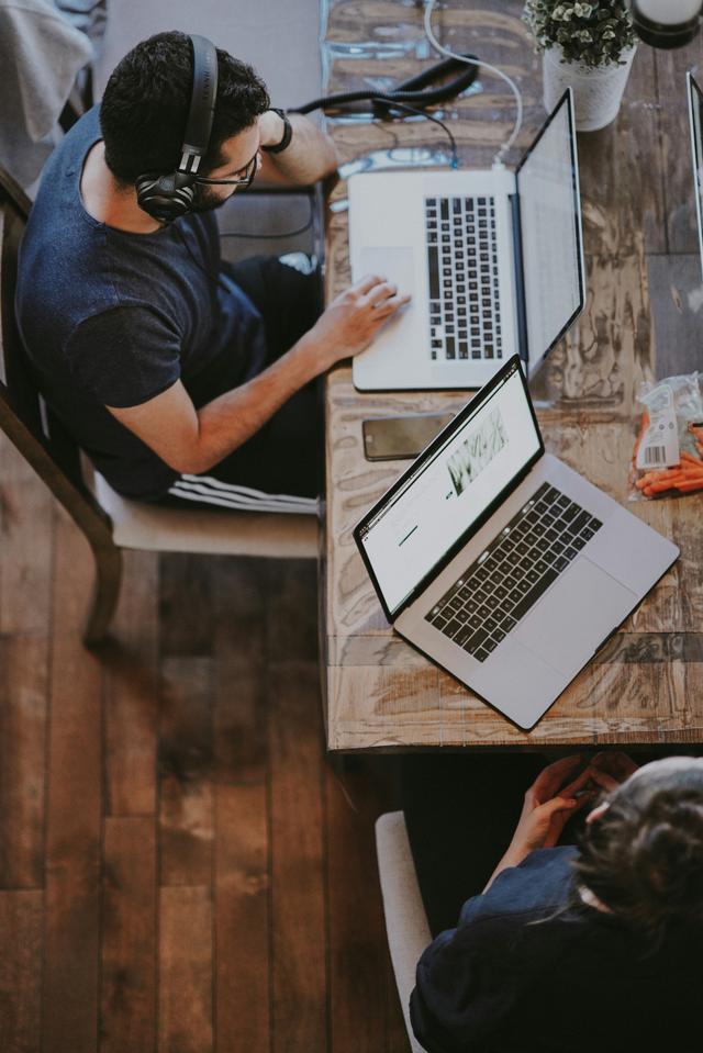 Person with headphones working at wooden table